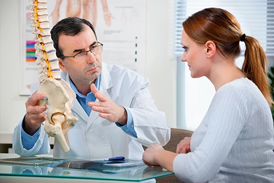 Chiropractor Gesturing To Spine Demonstratively