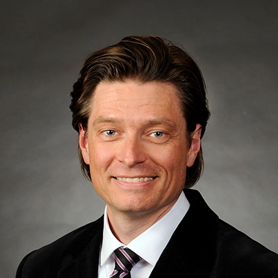 Chiropractor Seth Anderson Smiling In Black Suit With Black & Pink Tie